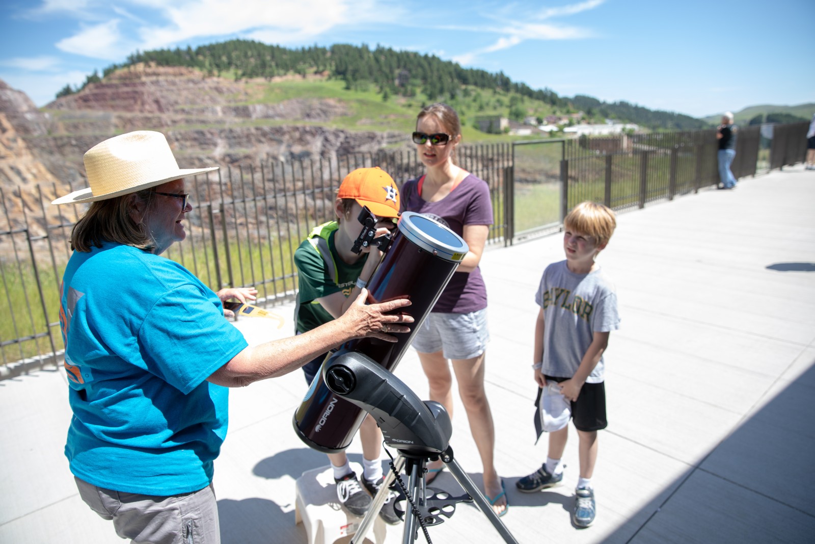 Neutrino Day volunteer helps visitors peer through a solar telescope 